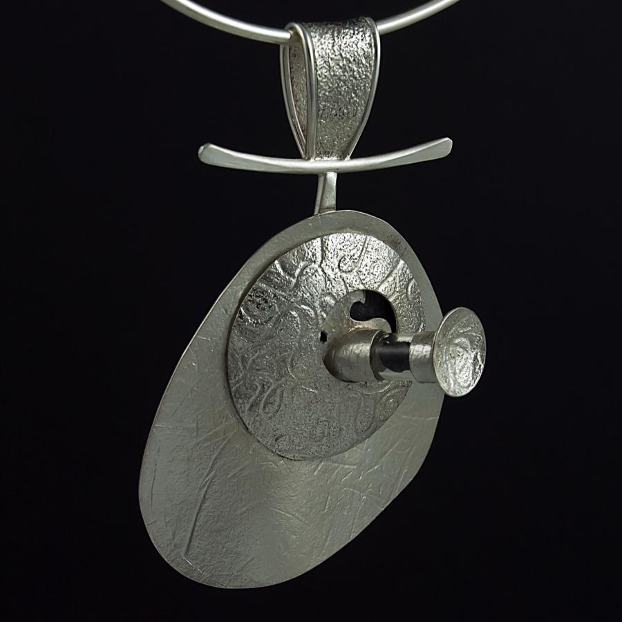 Silver pendant necklace on a black background.