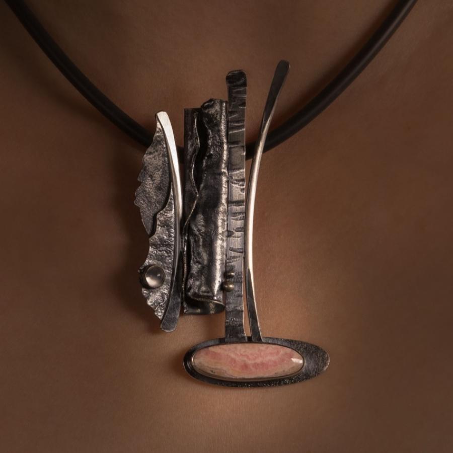Abstract silver necklace with pink stone on woman.