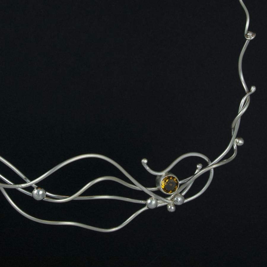 Silver necklace with amber colored gem.