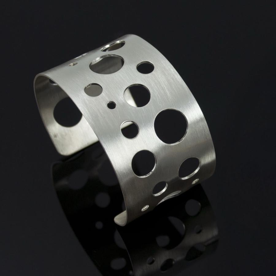 Silver cuff bracelet with circular holes, photograph.