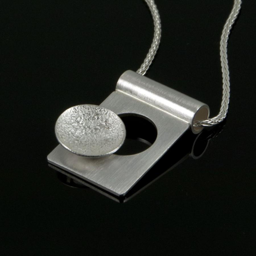 Silver pendant necklace on black background.