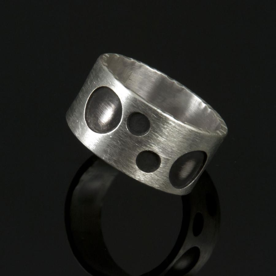 Silver ring with circular cutouts, photograph.