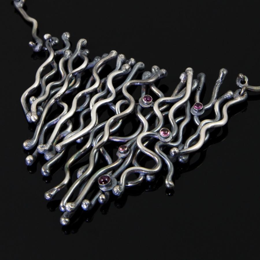 Silver necklace with red accents, studio shot.