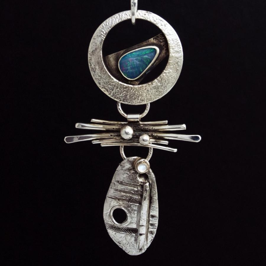 Silver pendant necklace with blue stone on black background.