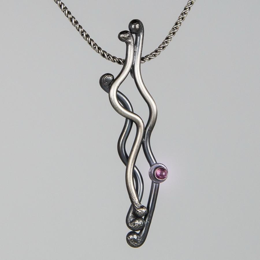 Silver necklace with abstract pendant and pink gemstone.