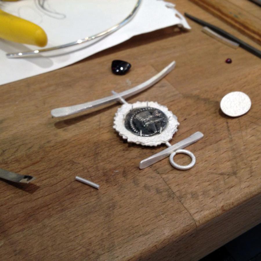 Jewelry in progress on a wooden workbench.