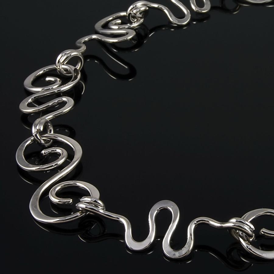 Silver necklace with abstract swirls, photograph.