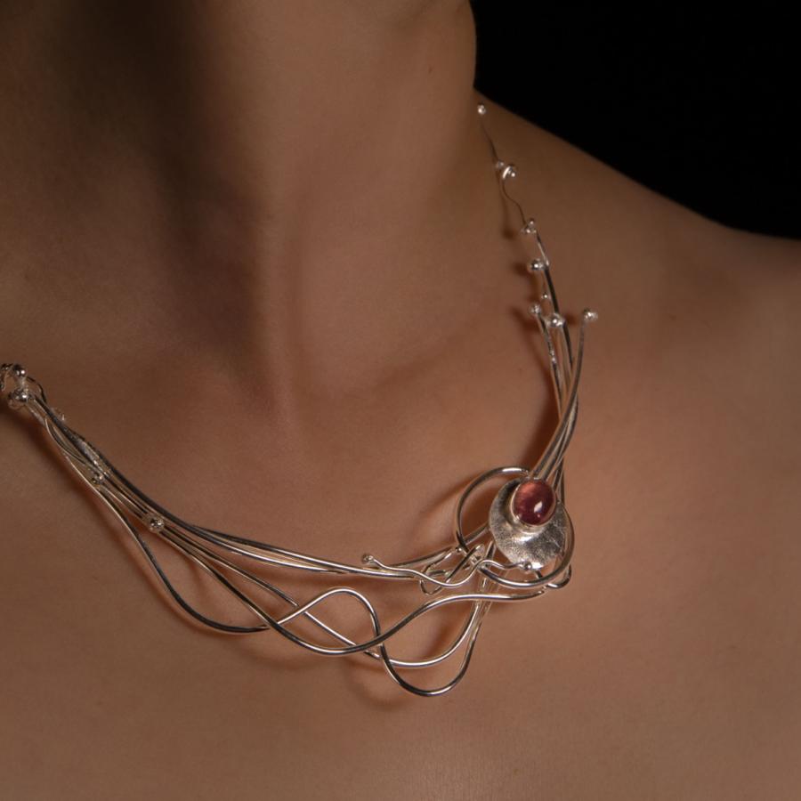 Necklace with pink stone on person.