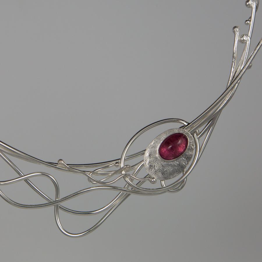 Silver necklace with a pink gemstone, studio shot.