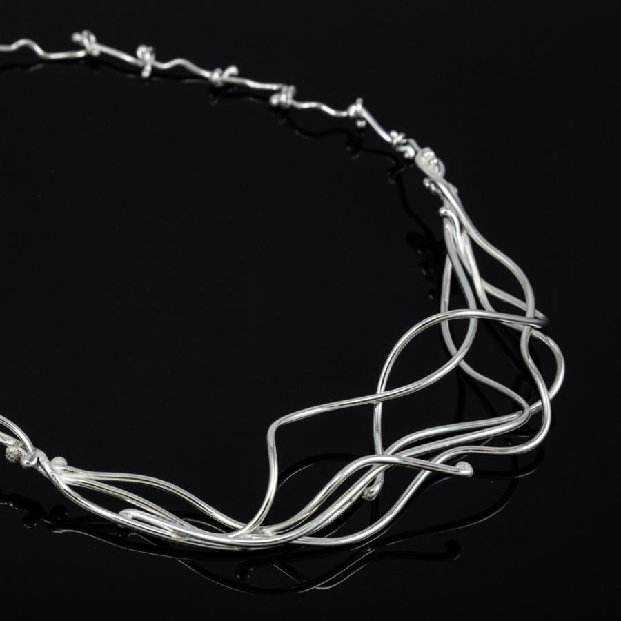 Silver necklace on a black reflective surface.