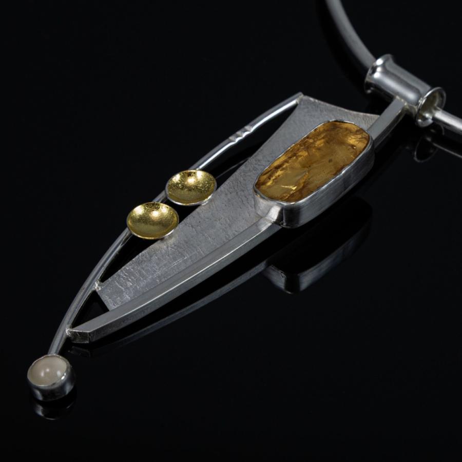 Modern silver necklace with amber stone, studio photograph.