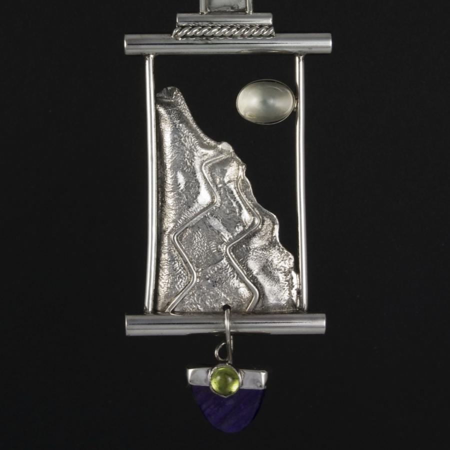 Silver pendant of mountain, moon, gemstone on chain.