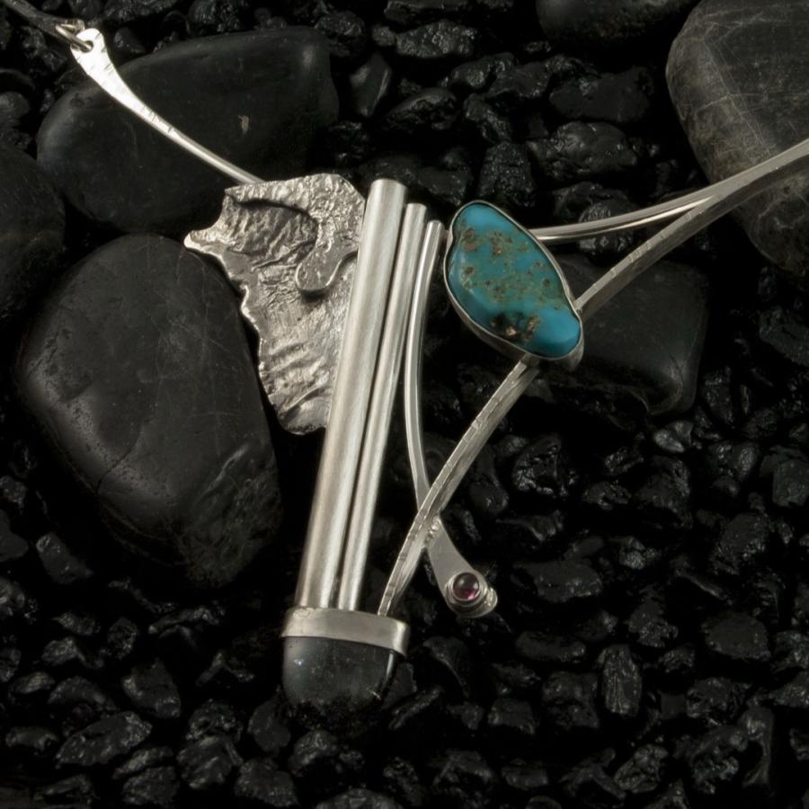 Silver necklace with an turquoise on black rocks.
