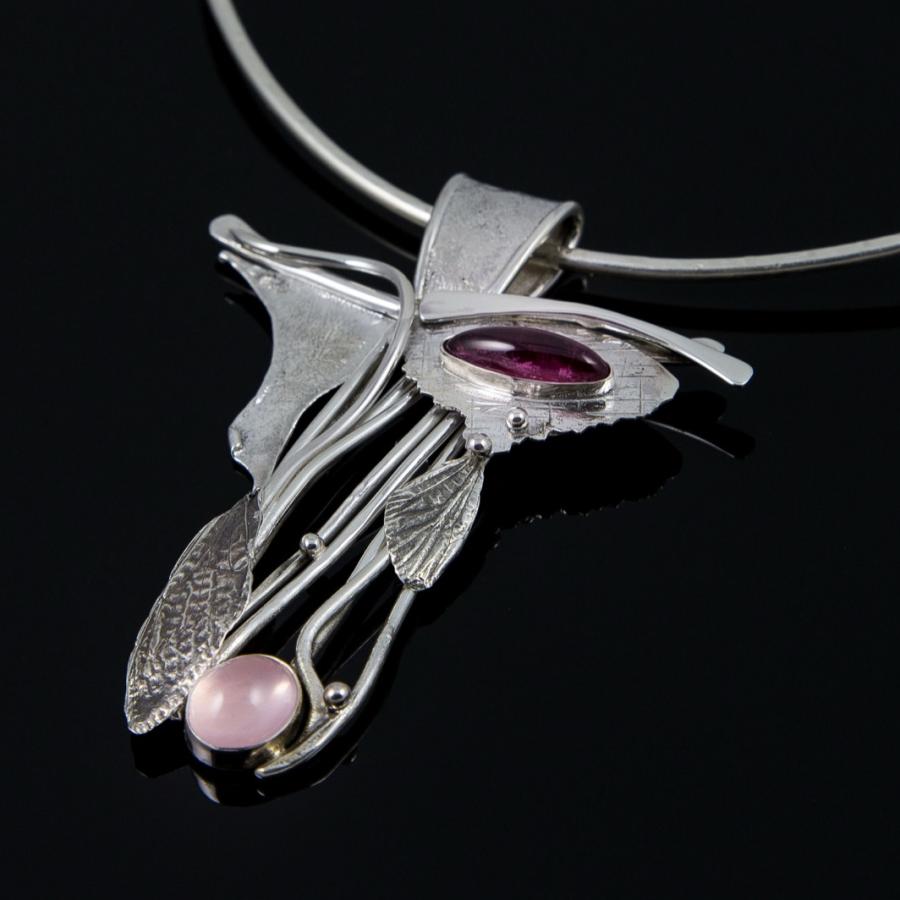 Silver pendant necklace with pink and purple gems.