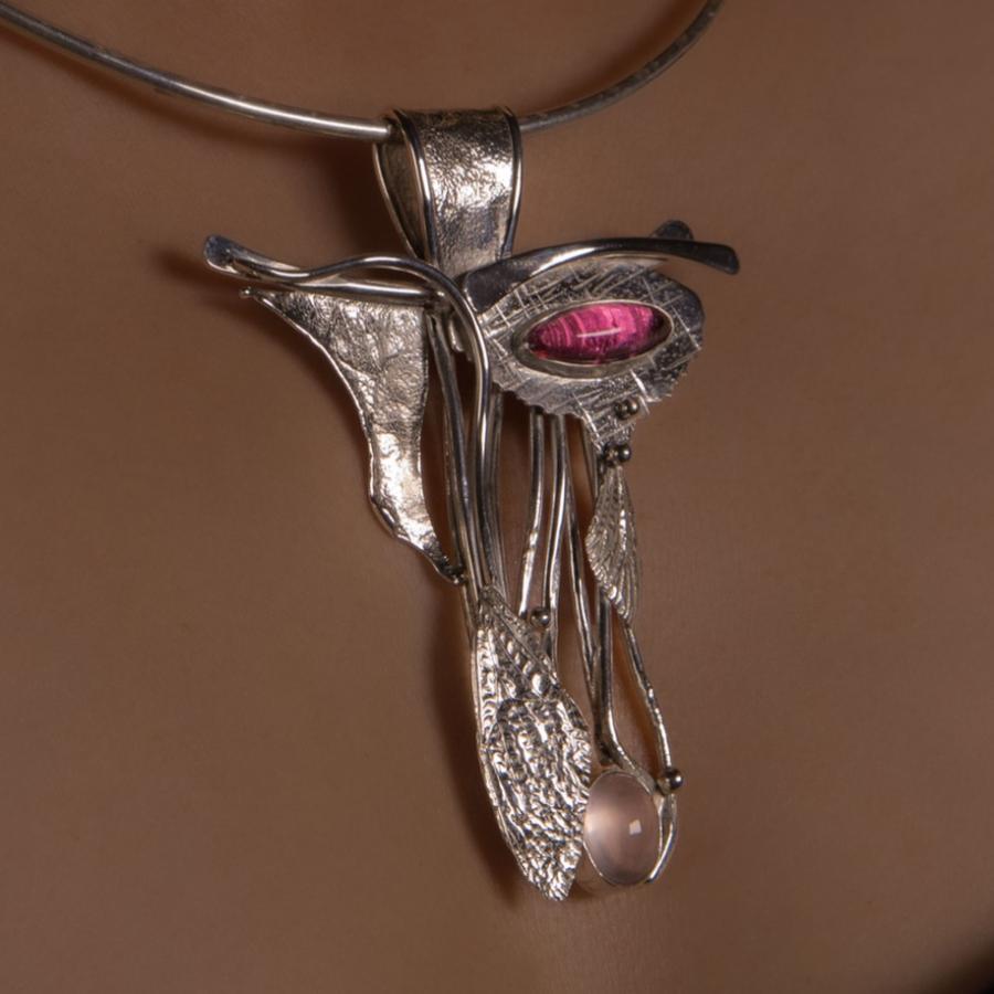 Silver necklace with pink stone on woman, photograph.