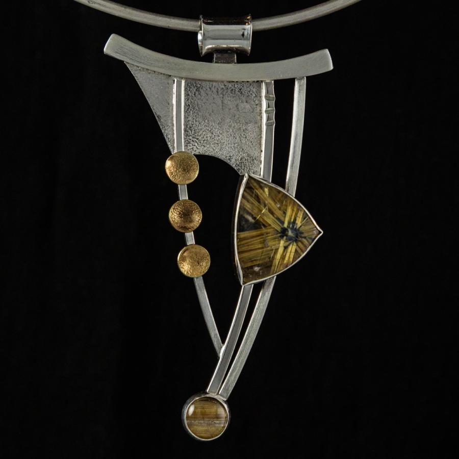Silver and gold pendant necklace, close-up photograph.