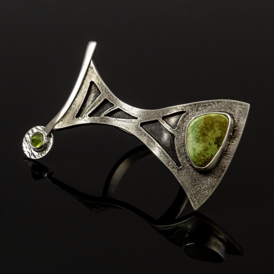 Silver ring with green stone on black background.