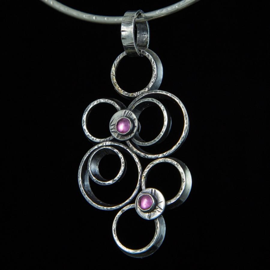 Silver necklace with circles and pink stones, photograph.