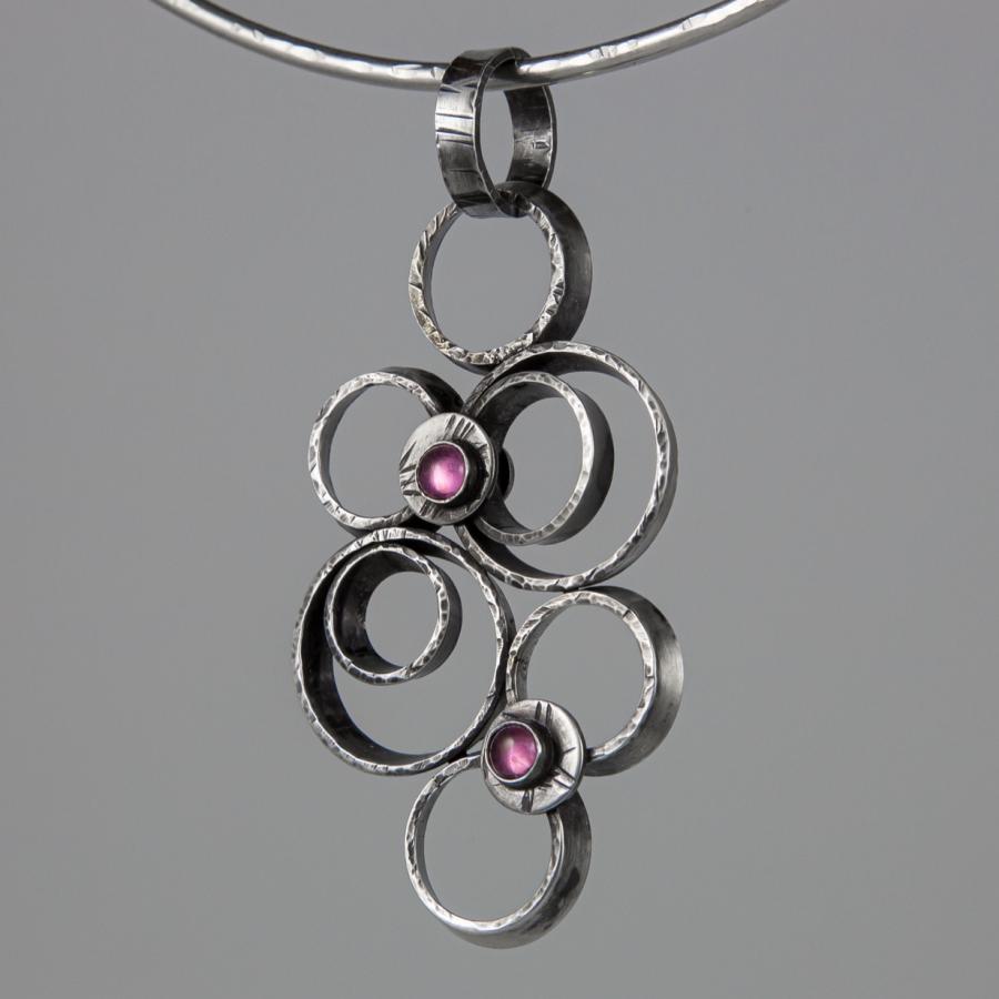 Silver pendant with pink stones, photograph.