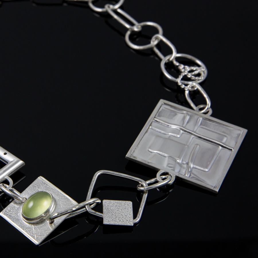 Silver chain necklace with geometric charms.