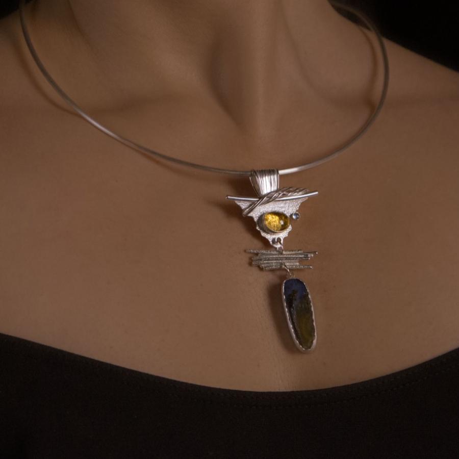 Woman wears a silver necklace with colorful stones.