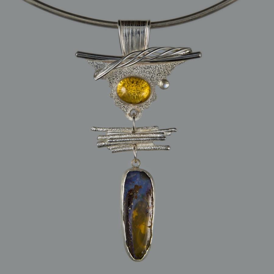 Silver pendant with yellow and dark blue stones, photograph.