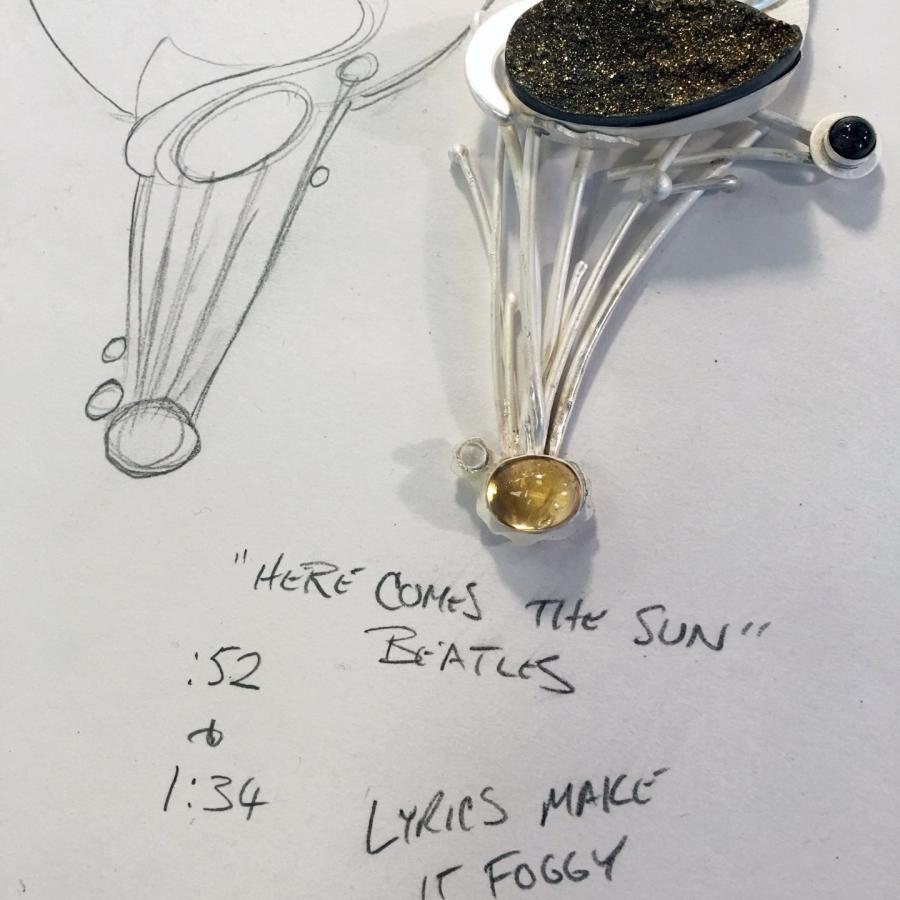 Pendant on paper with design drawing.