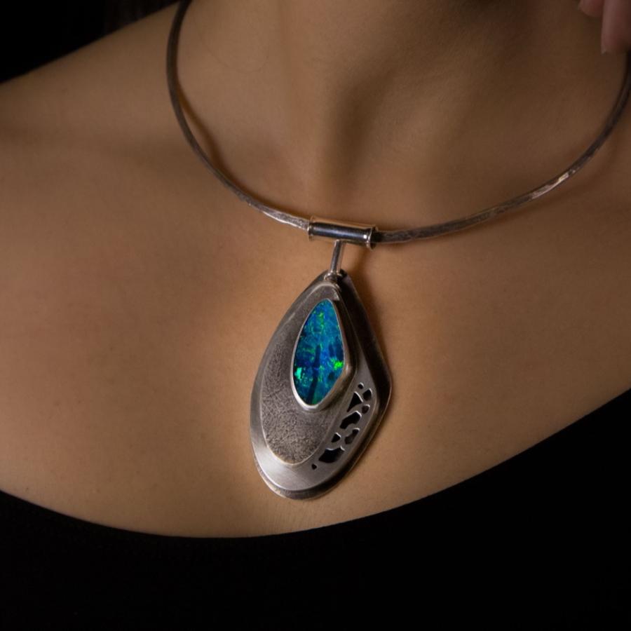 Woman wearing silver necklace with large tear-drop pendant.