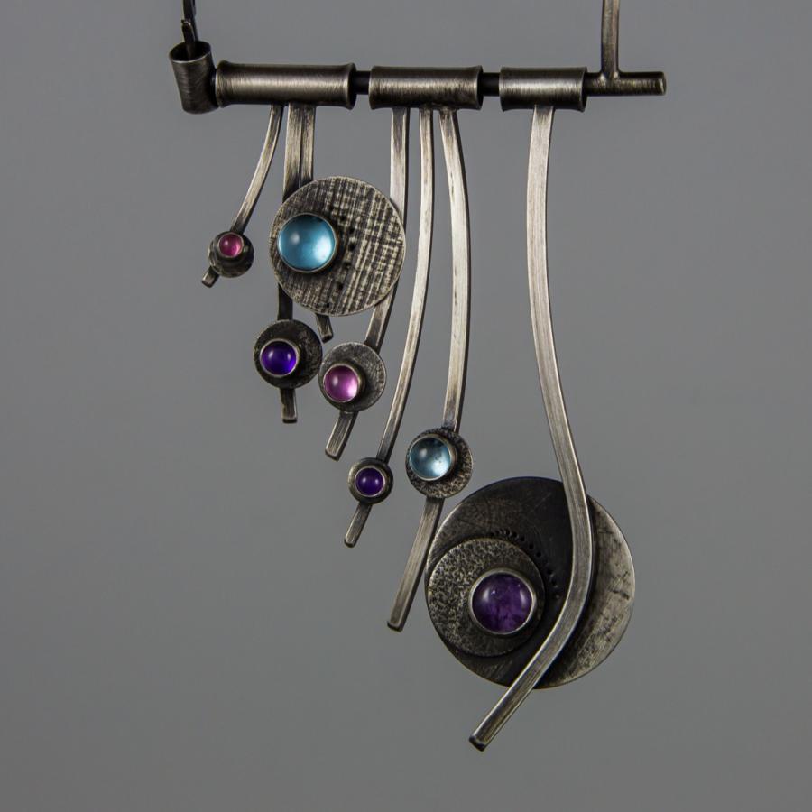 Silver pendant necklace with blue and purple stones.