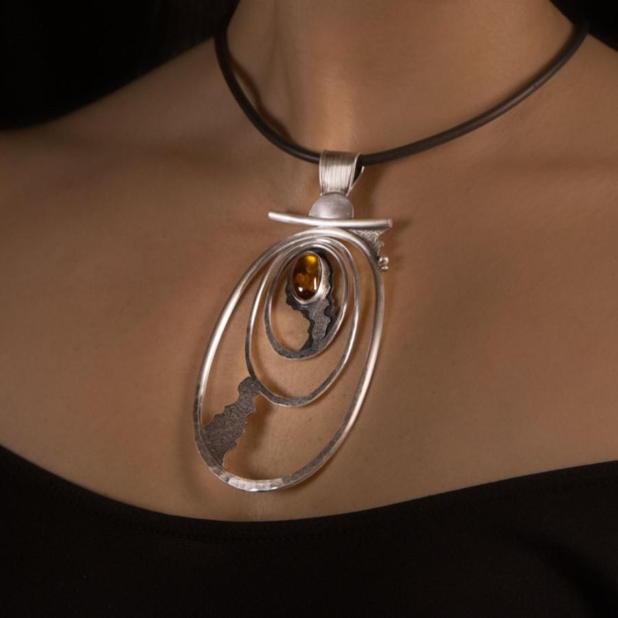 Woman wearing a necklace with a stone.