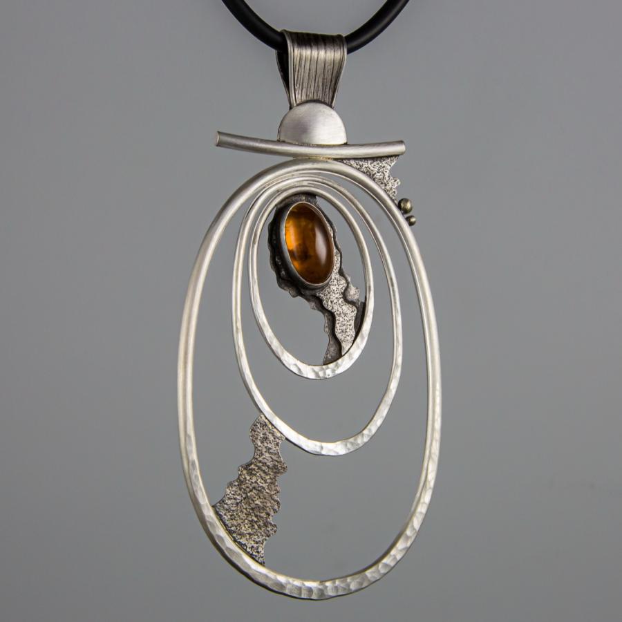 Silver pendant with amber stone on black cord.