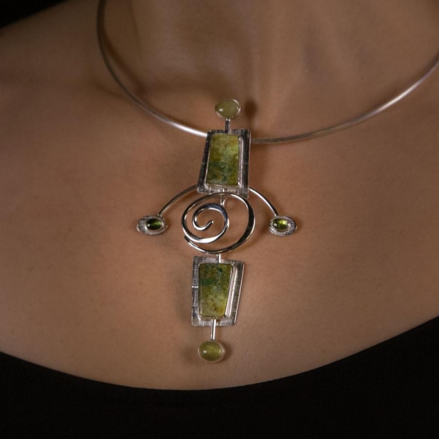 Woman wearing a silver and green pendant necklace.