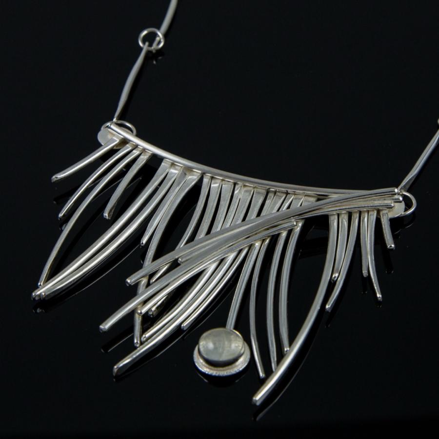 Silver necklace with dangling tines, studio photograph.