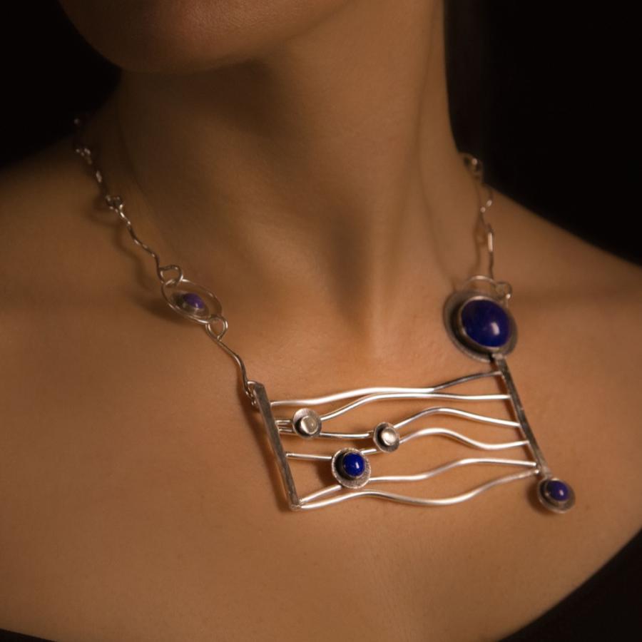 Woman wearing silver necklace with blue stones, photograph.