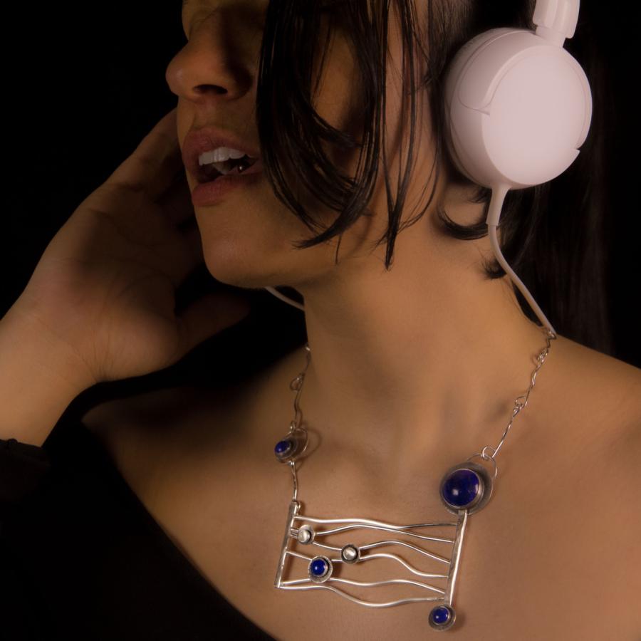 Woman listening to music with white headphones, silver necklace.