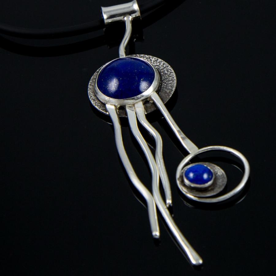 Silver necklace with blue stones on black background.