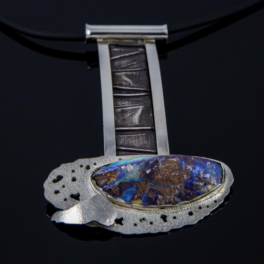Silver necklace with blue opal stone on black background.