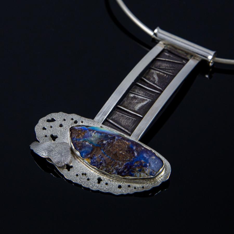 Silver necklace with blue and brown stone pendant, photograph.