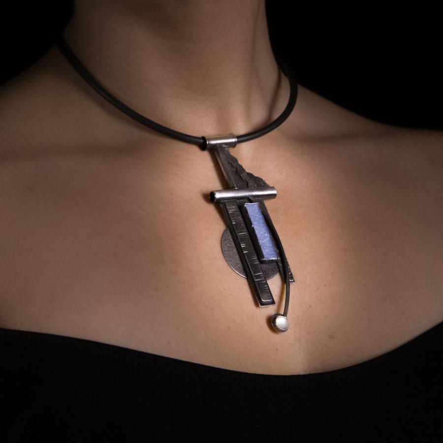 Woman wearing unique pendant necklace, studio shot.