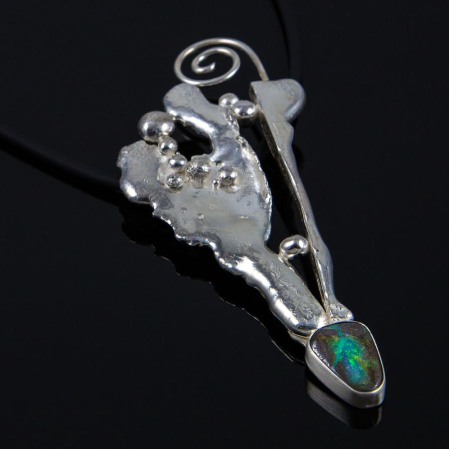 Silver pendant on a black cord, photograph.