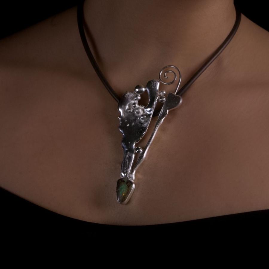 Woman wearing a silver necklace on a black background.