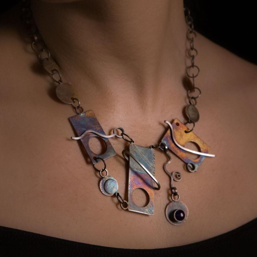 Woman wearing a colorful, handcrafted metal necklace.