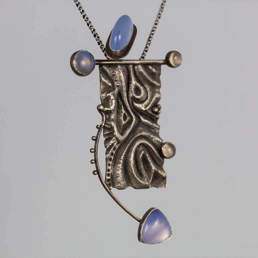 Silver pendant on white background with blue stones