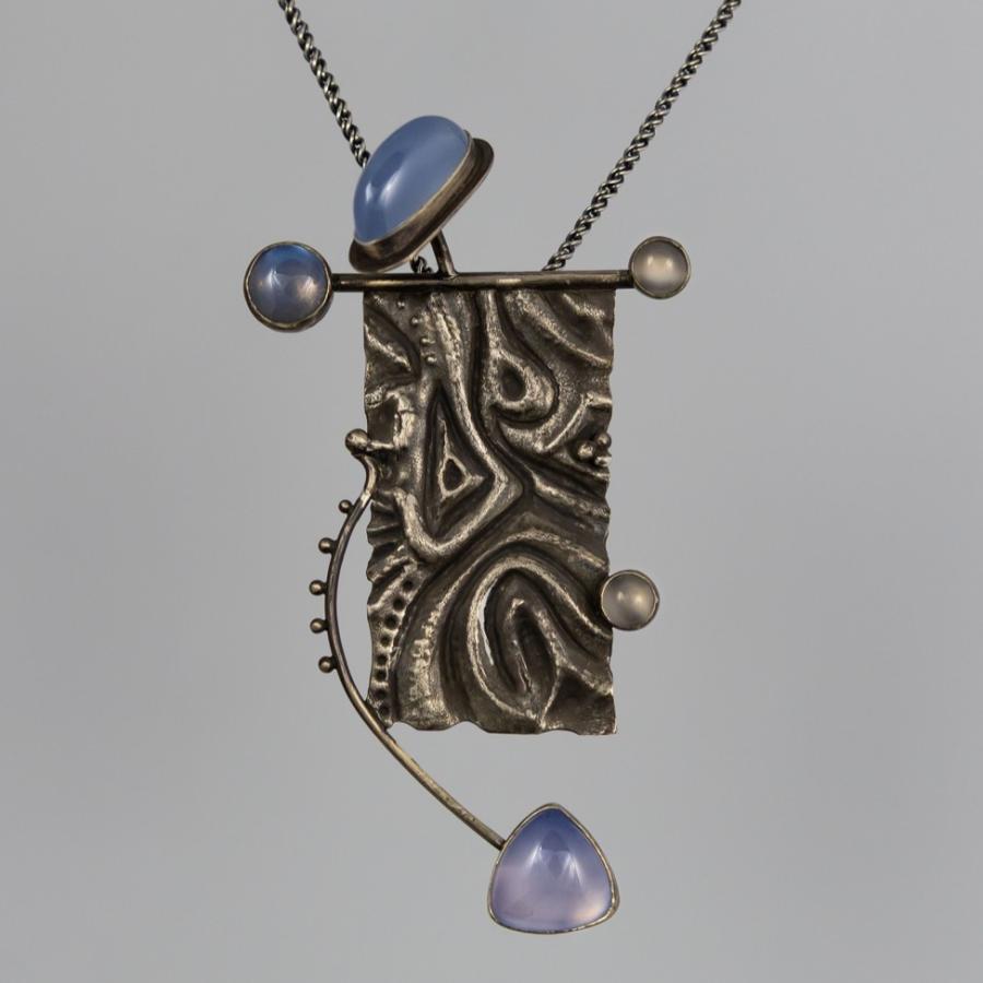 Silver pendant on white background with blue stones