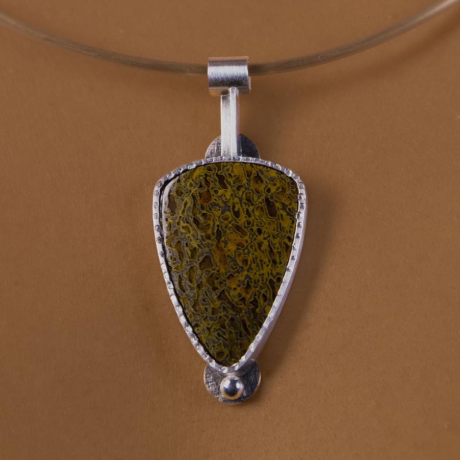 Woman wearing a silver pendant with a mottled brown stone