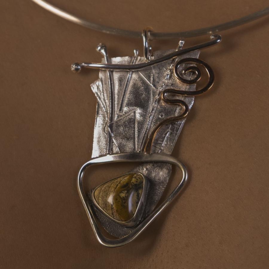 Woman wearing a silver and copper pendant with brown stone
