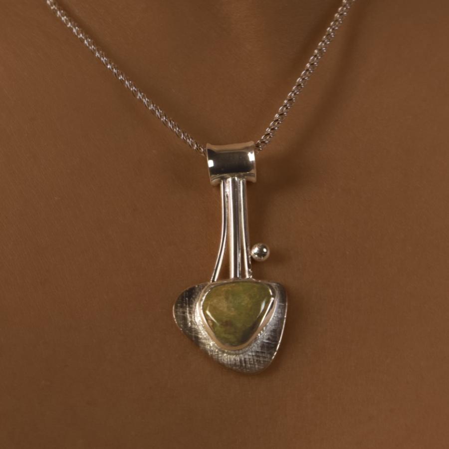 Silver pendant with brown, green stone worn by a model