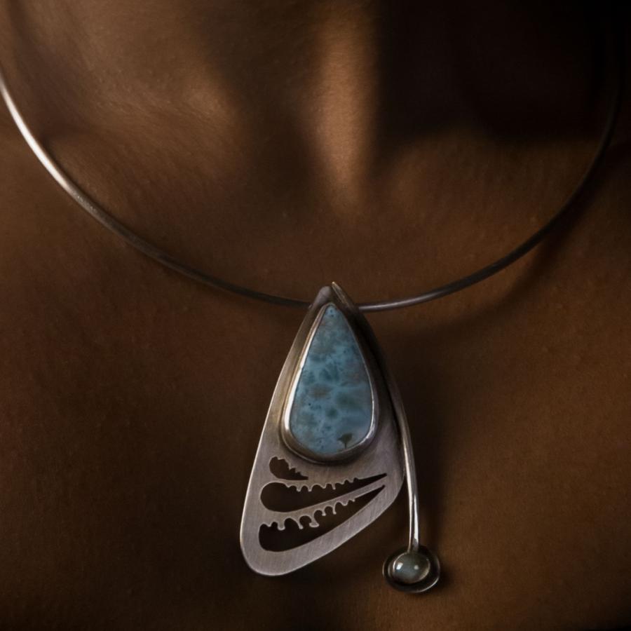 Model wearing a silver pendant with blue stones