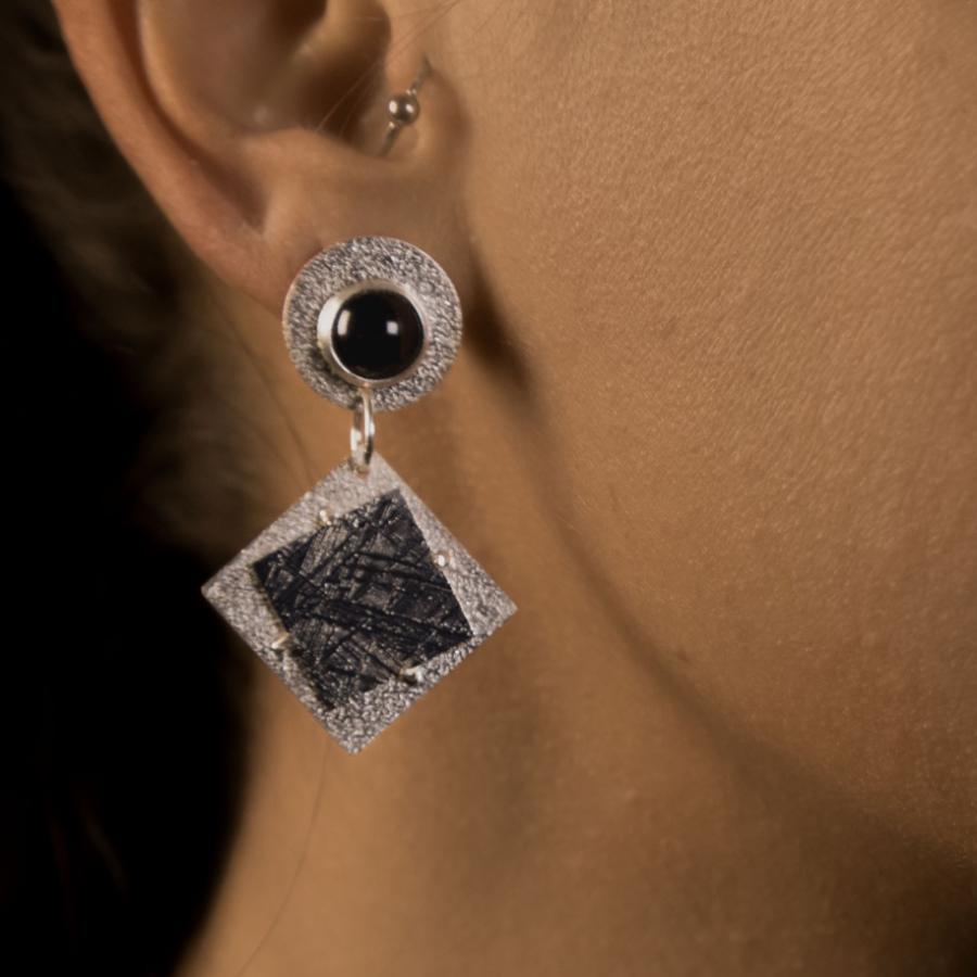 Model wearing silver earrings with black stones