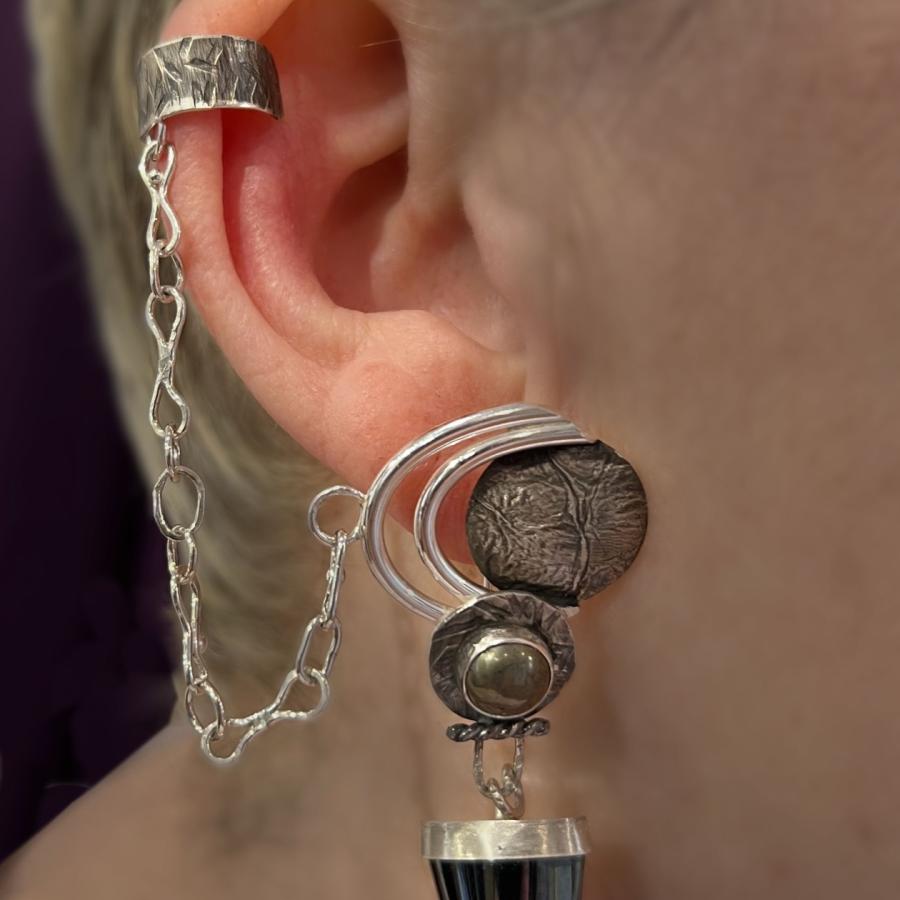 Earring connected to an ear cuff with a chain worn by a model